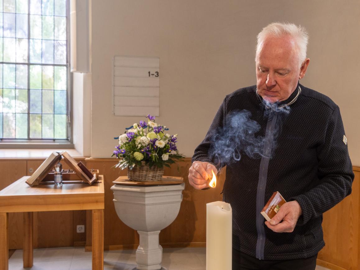 Sigrist zündet in seiner Kirche eine Kerze an.