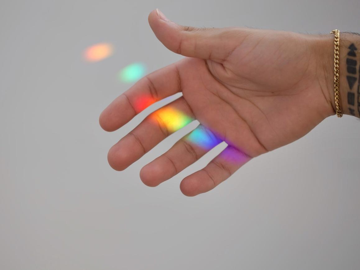Menschliche Hand mit Regenbogen-Lichtreflexen