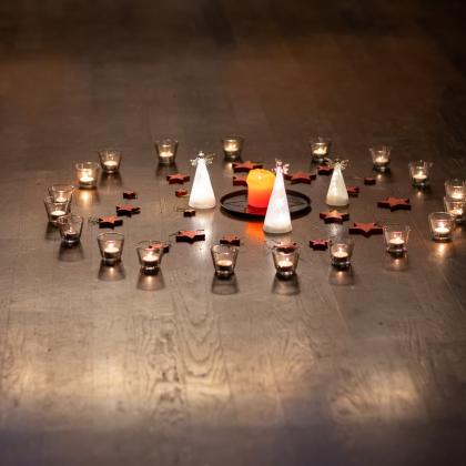 Brennende Kerzen stehen im Kreis am Boden