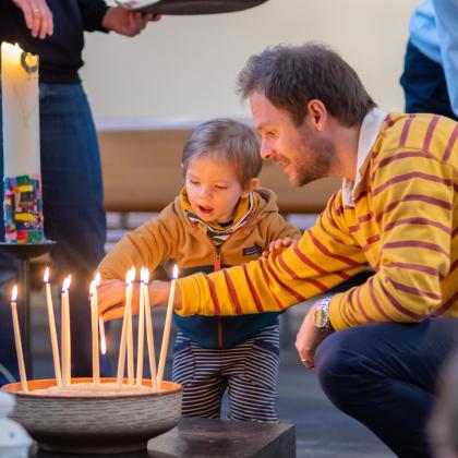 Vater zündet Kerze an mit Kind